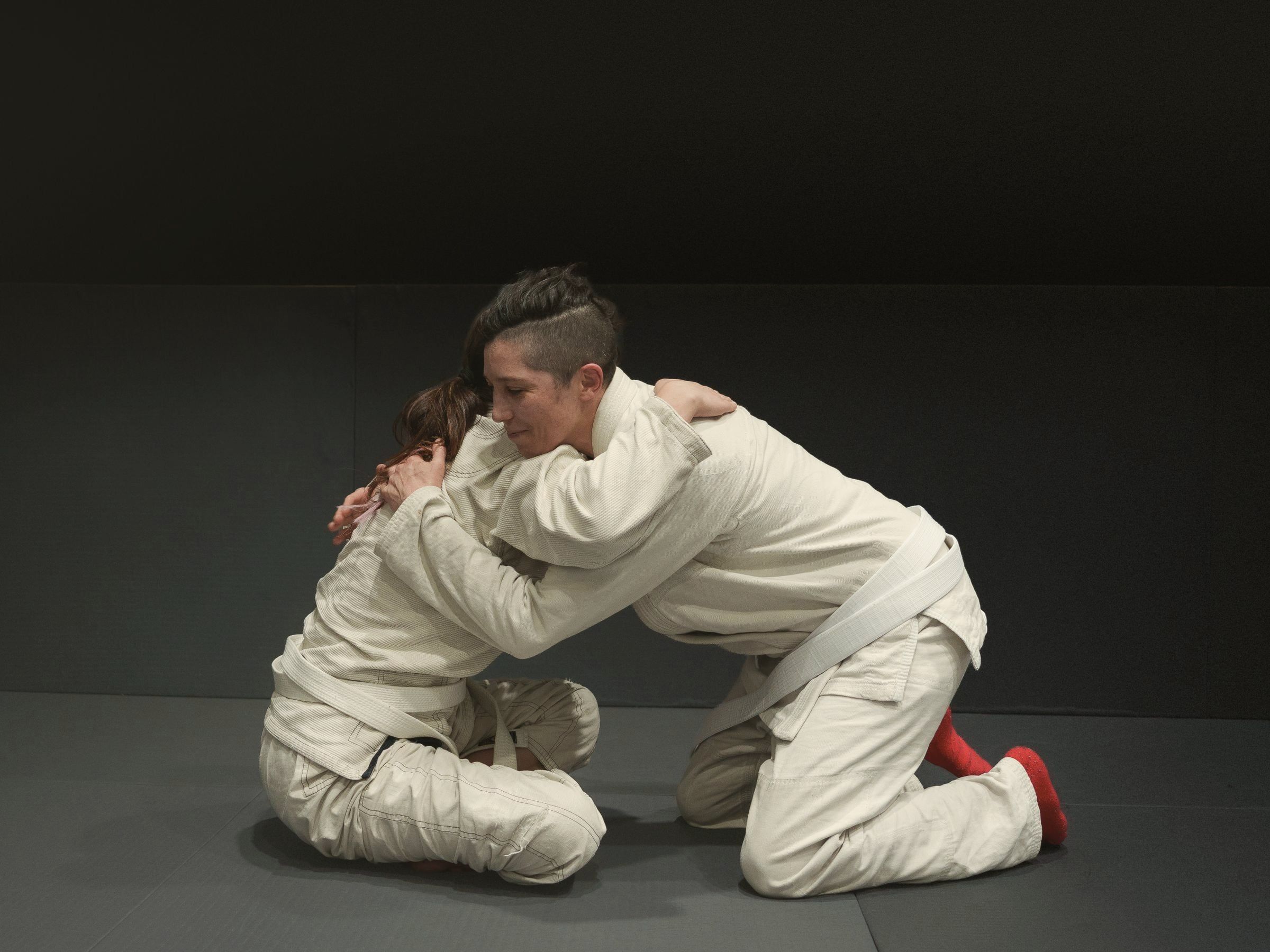 Dois praticantes de jiu-jitsu de joelhos disputando a pegada no início do rola