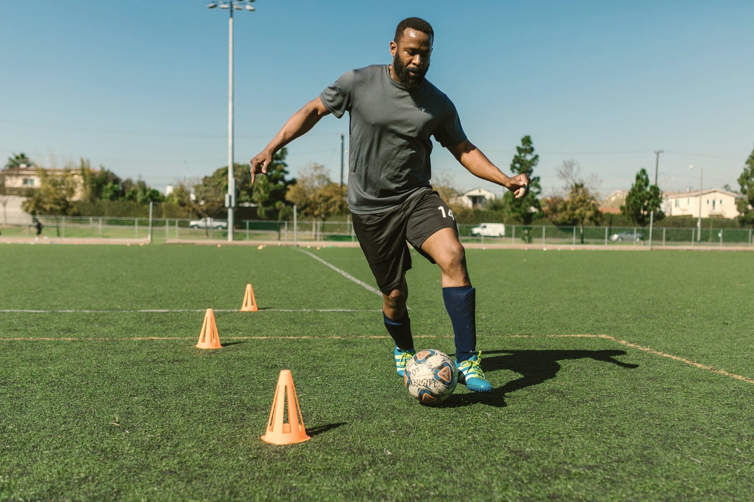 Jogador de futebol fazendo treino de mudança de direção entre cones