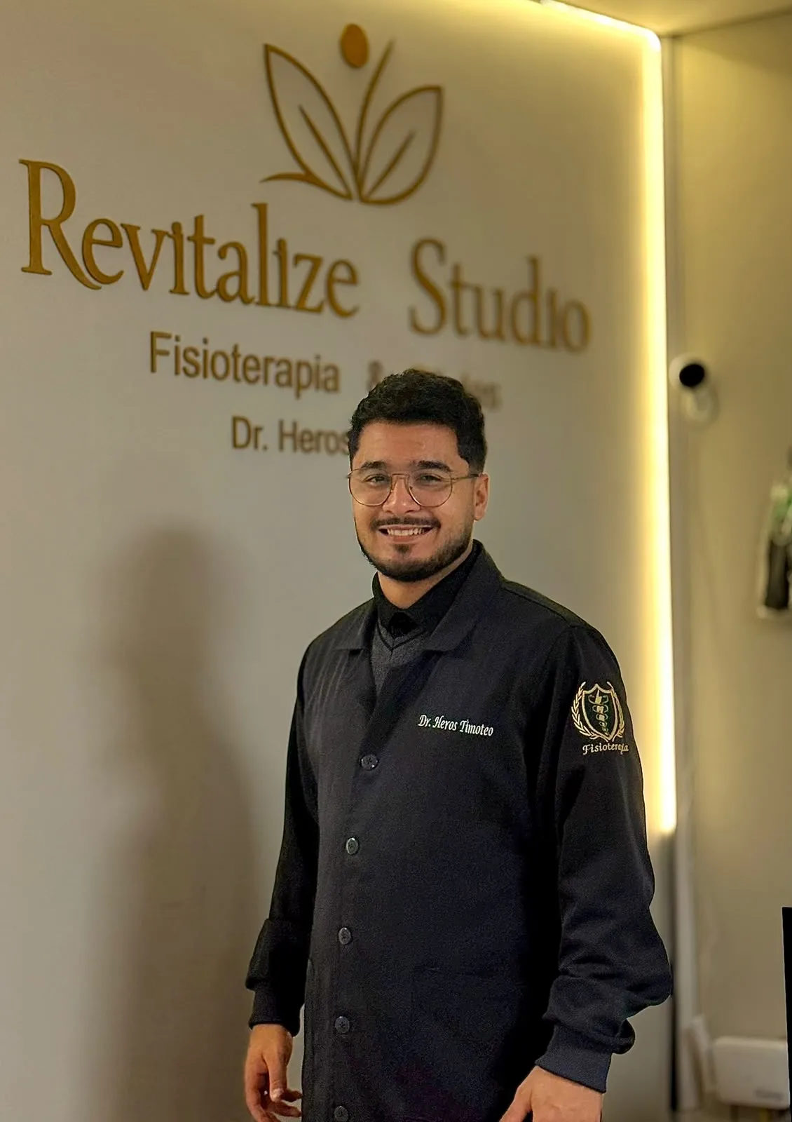Dr. Heros Timoteo, fisioterapeuta, em frente ao letreiro do Revitalize Studio