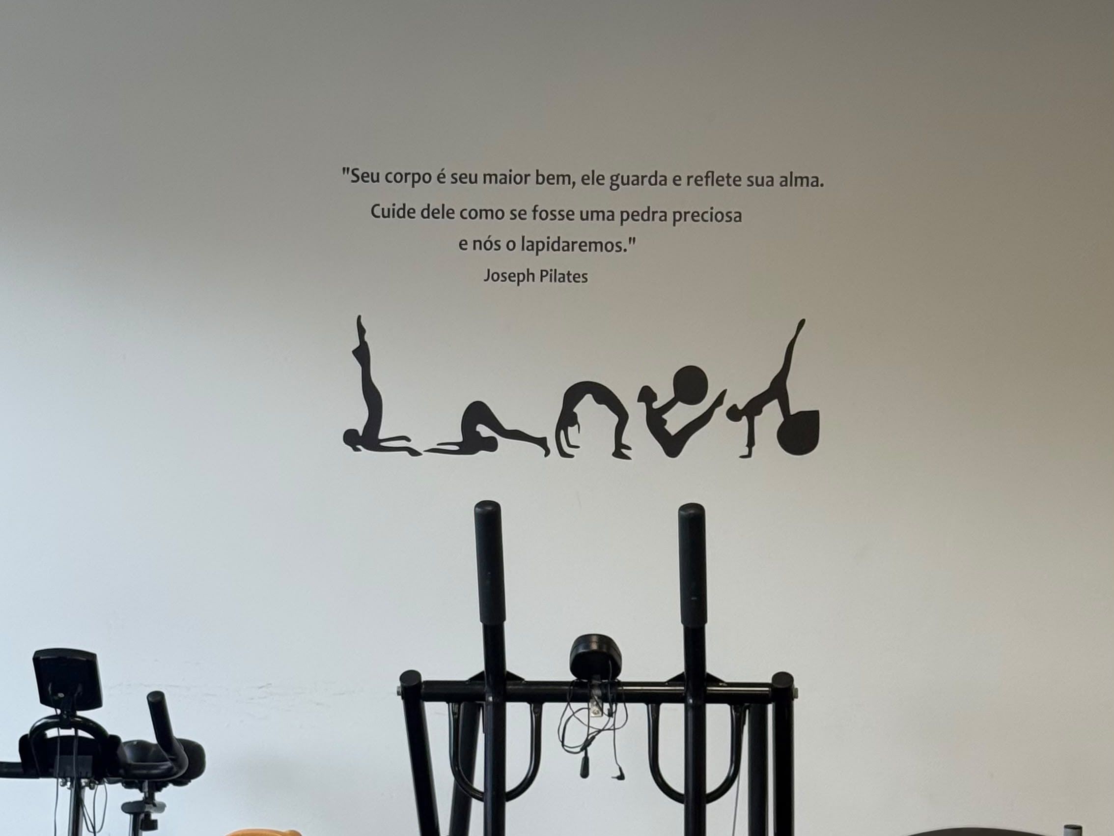 Frase de Joseph Pilates e silhuetas de exercícios na parede do Revitalize Studio